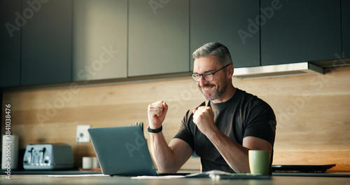 Photos Mature man, fist pump and laptop at house with good news, financial freedom and lotto winner