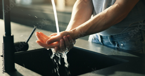 Person, washing hands or rinsing in kitchen with water for hygiene, disinfection or bacteria prevention. Man, wellness or cleaning skin in home with faucet for liquid, dermatology or germ protection.