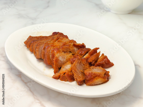 Sliced red pork on a white dish in a restaurant. Delicious chinese food.