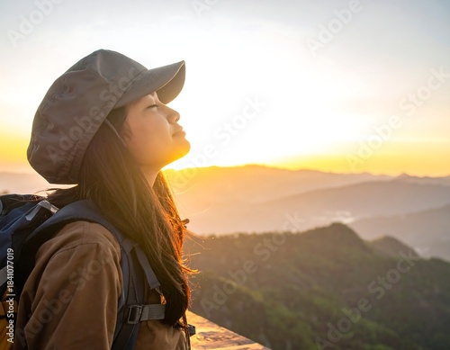 A woman on a mountain peak gazes up at a beautiful sunset