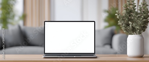 Laptop with blank white screen on wooden table in modern living room interior with sofa and plant for online business and remote work concepts