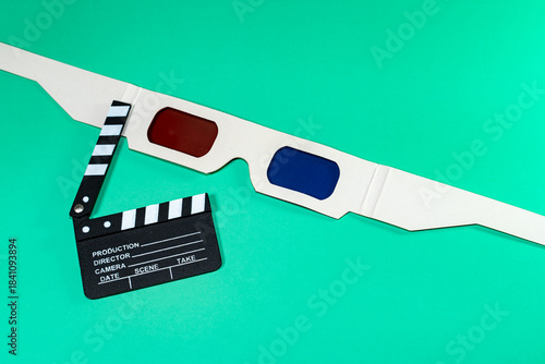 A composition featuring a clapperboard with 3D glasses, all set on a vivid green background, highlighting cinema.
