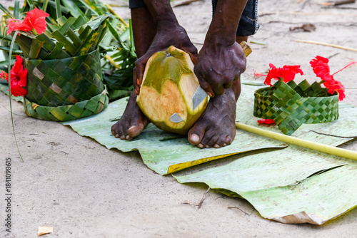 Young man peeling coconut fruit at the farm at Zanzibar island