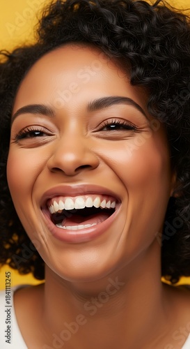 A joyful woman with a wide smile and bright eyes radiates happiness against a vibrant yellow background.