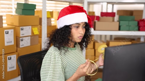 Small business warehouse, Christmas season with female staff offering festive gift, presenting holiday package with cheerful expression and supporting ecommerce order preparation in seasonal workspace