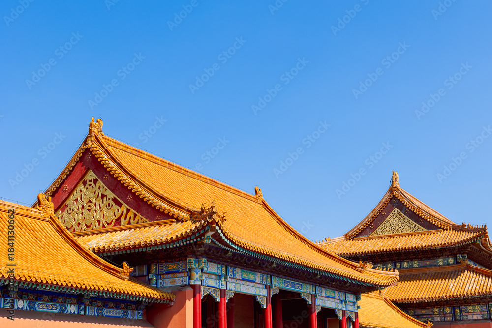 Naklejka premium Sunlit golden roof with ornate ridge figures and vivid painted beams provides clear view of traditional Chinese imperial architecture in Forbidden City, Beijing, China