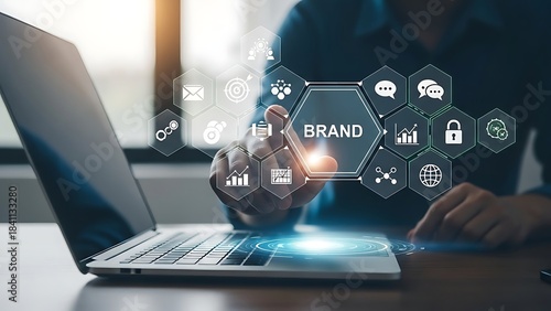 Business professional analyzing digital brand strategy on laptop with futuristic technology icons in modern office environment