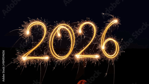 Glowing yellow fireworks spelling out twenty twenty six in night sky with sparks