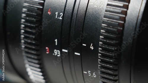 Close up shot of professional camera lens with focus distance and aperture dial and grip wheel. The aperture wheel rotating slowly adjusting the aperture number