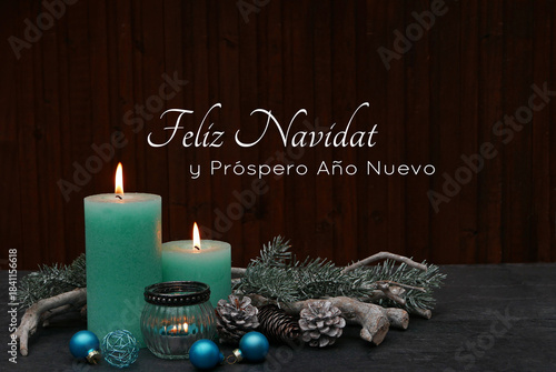 Tarjeta navideña en español: Velas turquesas encendidas con adornos navideños sobre un fondo de madera. Feliz Navidad y próspero Año Nuevo.