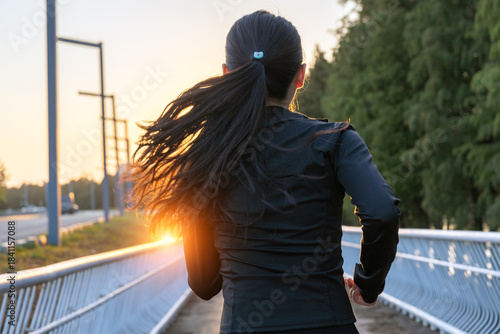 Young Asian girl running and exercising towards the sunshine on the greenway