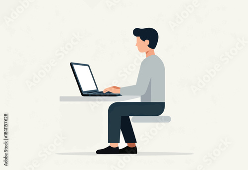 A person with dark hair, a gray shirt, and dark pants sits at a desk with a laptop. Their hands on the keys