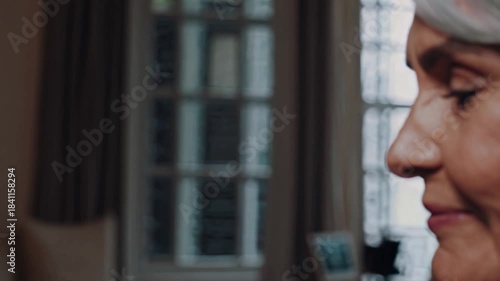 Elderly woman smiling warmly in a cozy indoor setting during afternoon light