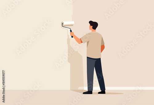 A person, viewed from behind, paints a wall with a roller. The shadow falls on the beige floor