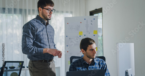 Team adult male engineer collaborate on robotic hand project using AI code solutions machine learning at tech workspace. Artificial intelligence interface, collaboration support prototype development.