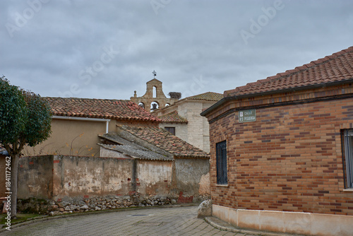 Stone bell tower with a cross and stork's nest at the Church of Saint Martin of Tours in Banos de Cerrato
