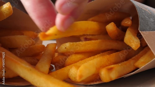 Closeup child fingers picking up eating French fries potato chips in fast food restaurant