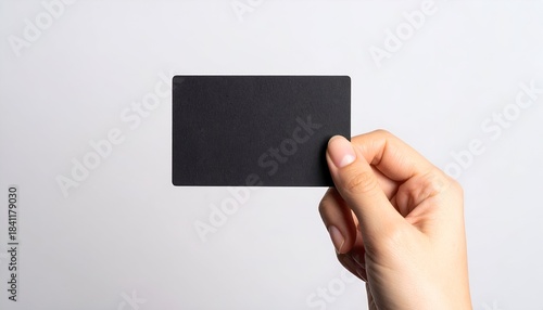 A hand holds a blank, black rectangular card against a plain white background