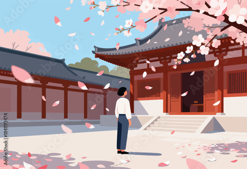 A person in a traditional Japanese garden watches falling cherry blossoms, near wooden temple