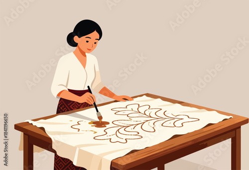 An artisan, wearing traditional attire, paints a botanical design on fabric atop a wooden table
