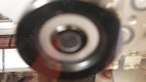 Chocolate bar travels on automated conveyor rails through packaging machinery in factory.