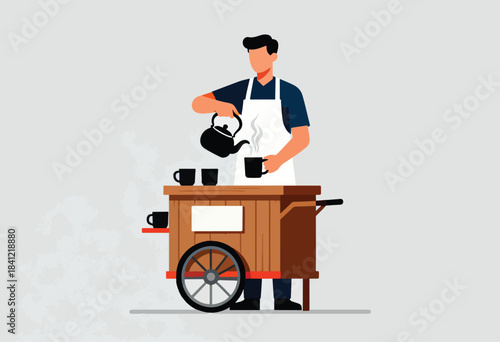 A man wearing an apron, pours tea from a black kettle into a mug, standing behind a wooden tea cart