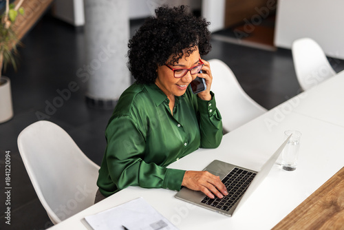 Obraz na płótnie Woman in Office on Phone and Laptop, Smiling and Working