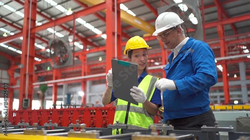 Factory workers reviewing production data together in an industrial plant.
