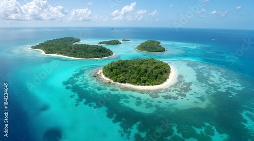 Aerial view of lush green tropical islands surrounded by vibrant turquoise and deep blue ocean water under a clear sky