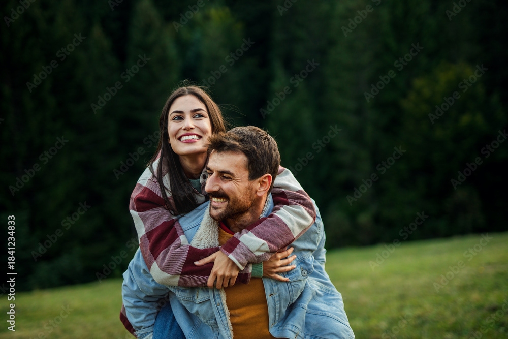 Obraz premium Young couple enjoying piggyback ride in nature