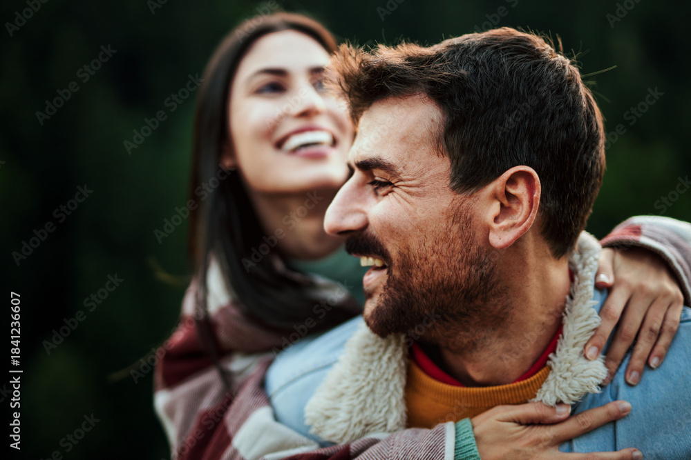 Fototapeta premium Happy couple enjoying outdoor piggyback ride on a trail