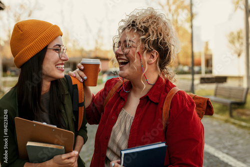 Female students laughing, enjoying coffee on campus