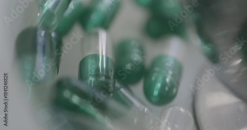 Empty transparent medicine capsules move along a sorting line. Close-up shot, real time speed, artificial indoors light.