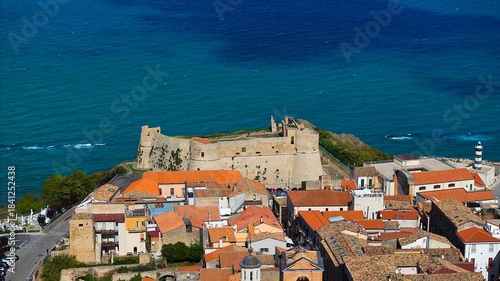 High-angle view of Ortona’s heritage streets framed by blue sky and gentle white clouds.