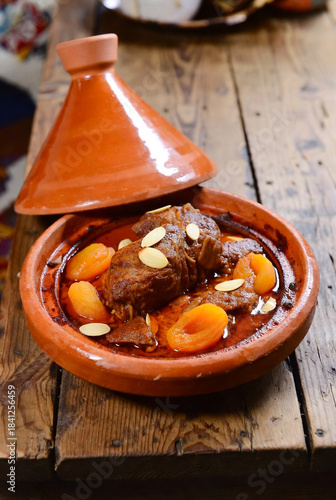 A hearty Moroccan tagine featuring tender lamb, sweet apricots, and toasted almonds simmered in a rich tomato-based sauce. Served in a rustic clay pot, inviting warmth and family-style sharing.