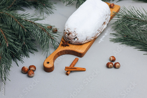 Christmas stolen in powdered sugar on a light background with pine branches and tangerines. Traditional Christmas delicacies. Top view