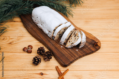 Christmas stolen in powdered sugar on a light background with pine branches and tangerines. Traditional Christmas delicacies. Top view
