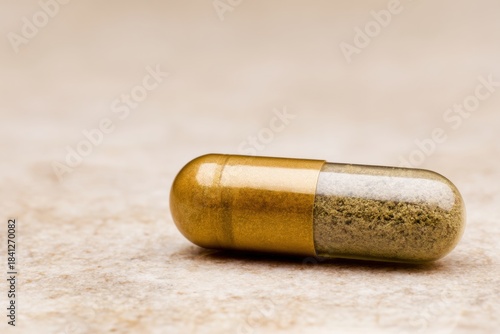Golden supplement capsule on neutral stone surface, perfect for product mockups, healthcare branding or pharmaceutical advertising.