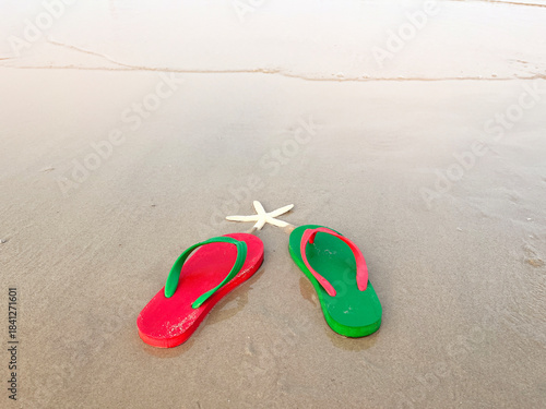 green and red sandals on summer beach background at sunset with copy space.