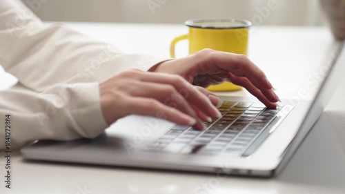 Woman typing on laptop keyboard, representing AI work, remote job, prompt creation, study, freelancing, and research, close-up view.