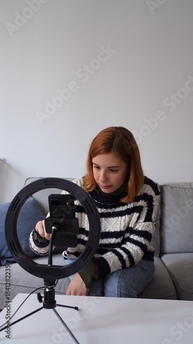Young female influencer setting up her smartphone on a ring light to start a live streaming session