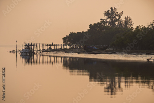 Sunset landscape view with wooden pier and boat at Kotka Point bordering Bay of Bengal, Sundarbans UNESCO world heritage mangrove, Mongla, Bangladesh