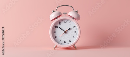 Vintage alarm clock against a pastel pink background.