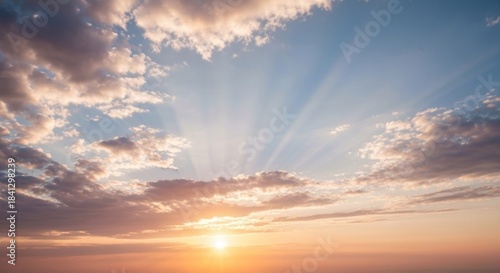 Sun bursting through clouds, creating golden rays and casting light over a blue sky