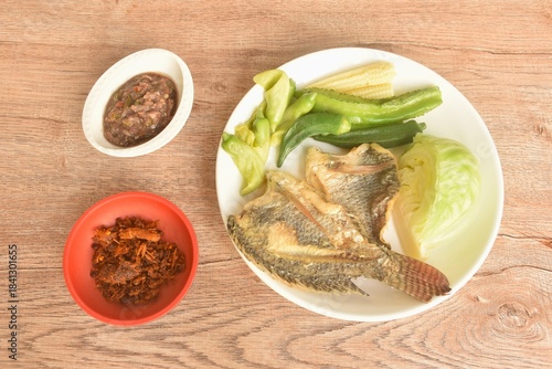 batter fried tilapia fish with boiled vegetable on plate dipping spicy shrimp paste sauce