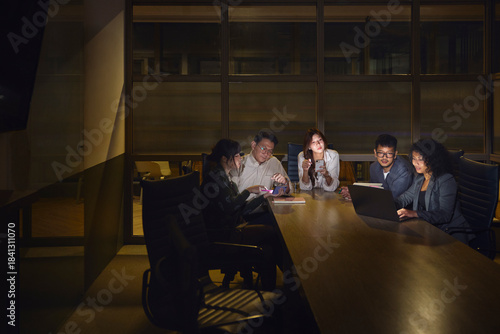 Team of business professionals planning strategies during late night office meeting in board room