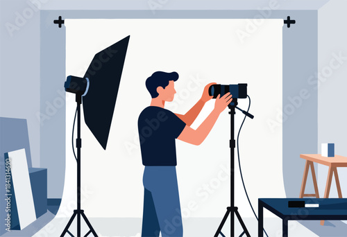 Photographer in studio operating camera in front of backdrop with lighting