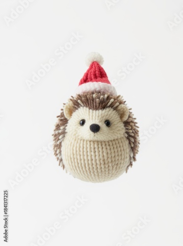 Adorable knitted hedgehog toy wearing a festive red Santa hat isolated on white background