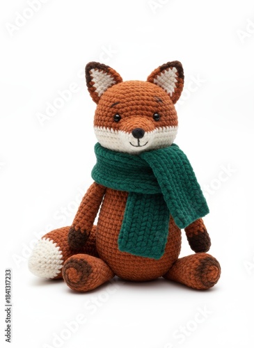 Handmade crocheted fox toy wearing a green scarf, sitting against a white background