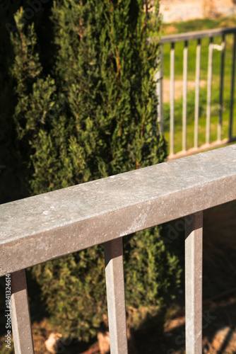 Empty metal balustrade for product composition against vibrant green bush. Nature concept for wallpaper, social media post or website.